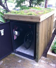 a bike is parked in the back of a wooden shed with plants growing on top