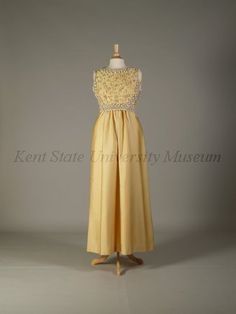 Pierre Balmain Haute Couture evening dress from French 1960-1970. Made from yellow silk satin peau de soie ground, yellow dome caps, embroidered  embroidery with bead, pearl, rhinestones, cream cord loops, white plastic lilies flower, light yellow braid trim,  and dome lucite button. Sleeveless floor length A line gown in scoop necked style.#Balmain #HauteCouture #Vintage #Fashion House of Balmain. Robert Piguet, Jean Patou