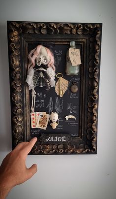 a hand is pointing at a framed skeleton