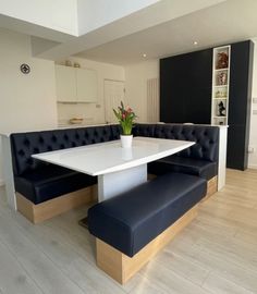 a white table and bench in a room with hardwood floors, black leather seats and an open floor plan