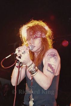 a man with long hair and tattoos on his arm singing into a microphone