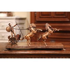 a bronze statue of two people on horses pulling a cart with a man in it