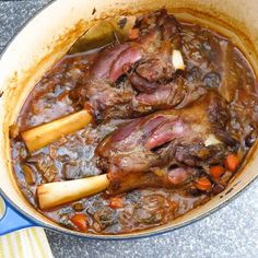 two pieces of meat in a pot with carrots and gravy on the side