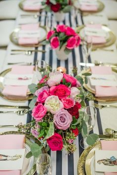 the table is set with pink and white flowers, silverware, and place settings