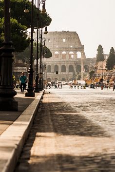 people are walking down the street in front of an old building with a roman collage on it