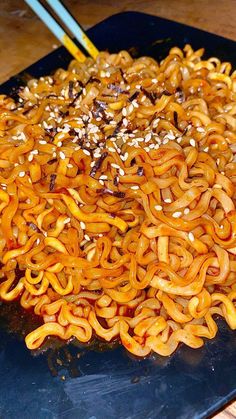 noodles with sesame seeds and chopsticks on a blue plate, ready to be eaten