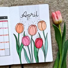 an open planner with flowers on it next to a pink tulip