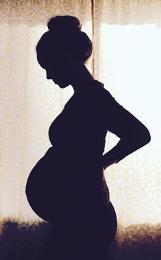 a pregnant woman standing in front of a window