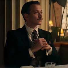 a man wearing a suit and tie sitting at a table