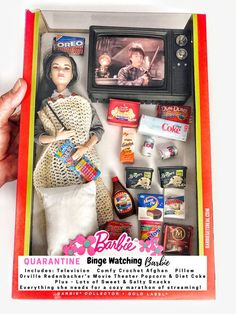 the barbie doll is in its box with other items around it, including an old tv