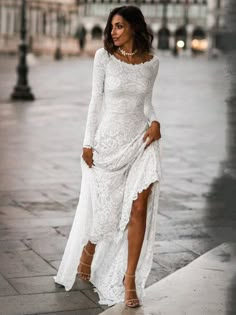 a woman in a white dress is walking down the street with her legs crossed and wearing high heels