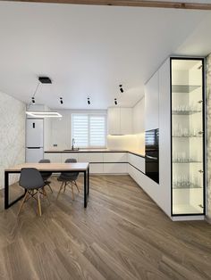 an empty kitchen and dining room with white walls, wood flooring and open shelving