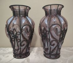 two glass vases sitting side by side on a table