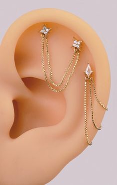 the ear is adorned with gold chains and three small diamond studs, which are attached to each other