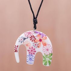 an elephant with flowers painted on it is hanging from a cord