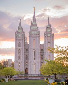 the mormon temple in salt lake city is lit up at dusk with pink and yellow clouds