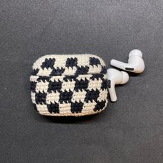 an earbud case made out of crochet with black and white hounds