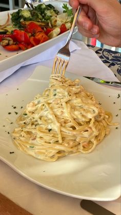 a person is holding a fork over some pasta