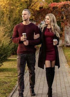 a man and woman walking down a sidewalk with coffee in their hands, both wearing boots