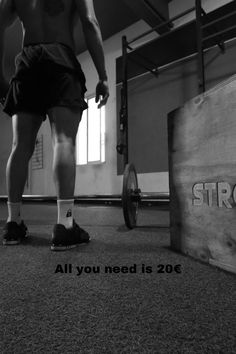 a man standing on top of a gym floor next to a barbell