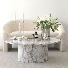 a marble coffee table with vases and candles on it in front of a couch