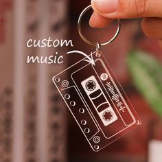 a hand holding a keychain with an image of a cassette tape on it