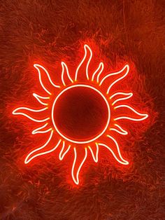 a neon sign that looks like the sun is glowing in the night sky with red light