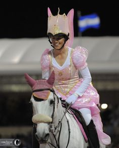 a woman in pink riding on the back of a white horse