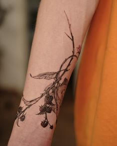 a tattoo on the arm of a woman with berries and leaves growing out of it