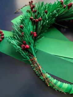 an origami wreath made out of green paper with berries and pine needles on it