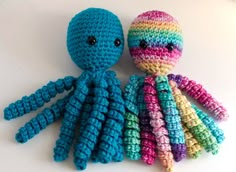 two crocheted octopus stuffed animals sitting next to each other on a white surface