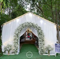 an outdoor wedding venue with white drapes and flowers on the front door, surrounded by greenery