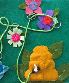 some felt flowers are sitting on a green table cloth with thread and sewing needles attached to them