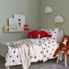 a teddy bear sitting on top of a bed next to a wooden table and chair