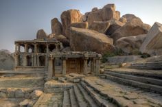 an old building surrounded by large rocks and stone steps in the middle of it,