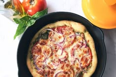 a pizza sitting in a pan on top of a table next to an orange bowl