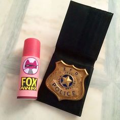 a pink lip balm next to a police badge