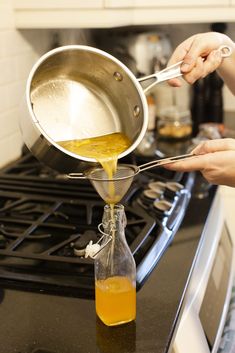 a person pouring liquid into a pot on top of a stove with a spatula