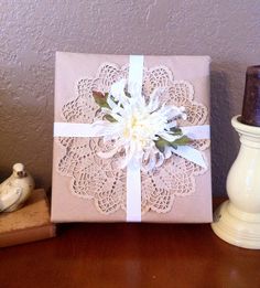 a gift wrapped in pink paper with a white flower on it sitting on a table