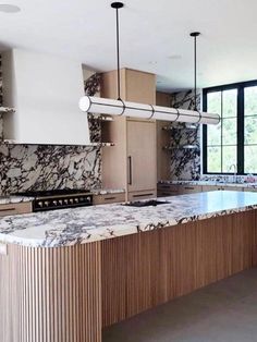 a large kitchen with marble counter tops and wooden cabinets, along with an island in the middle