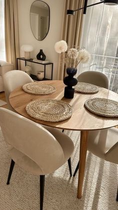 a dining room table with white chairs and plates on top of it in front of a large window