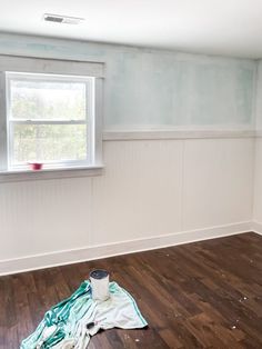 an empty room with wood flooring and paint on the walls, next to a window