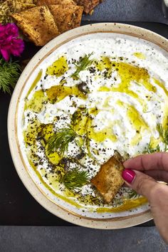 a bowl of hummus with sour cream and dill sprinkled on top