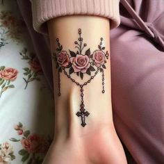 a woman's arm with a cross and roses tattoo on it