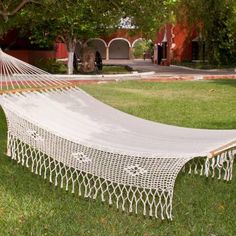 a white hammock sitting on top of a lush green field next to a tree