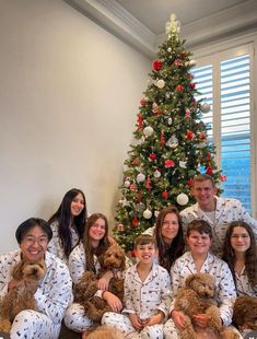 a group of people in pajamas posing for a photo next to a christmas tree