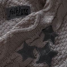 three black stars are on top of a white knitted sweater that says follow us