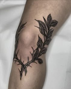 a black and white photo of a tattoo on someone's arm with leaves around it