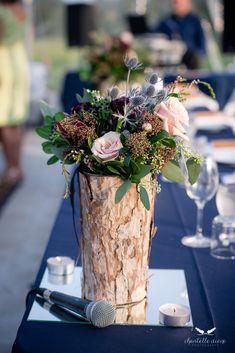 a wooden vase filled with flowers sitting on top of a blue table cloth covered table