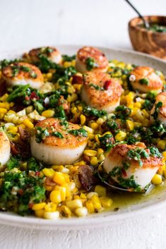 a white plate topped with scallops and corn